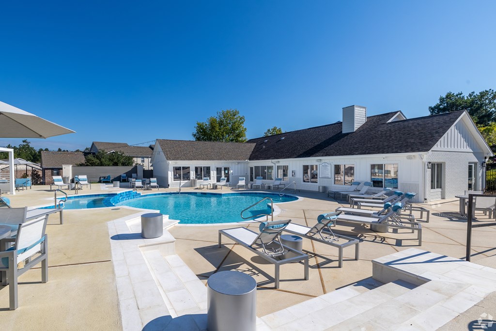 A large outdoor swimming pool with lounge chairs and a white building in the background. at Reserve at Park Place Apartment Homes, Hattiesburg
