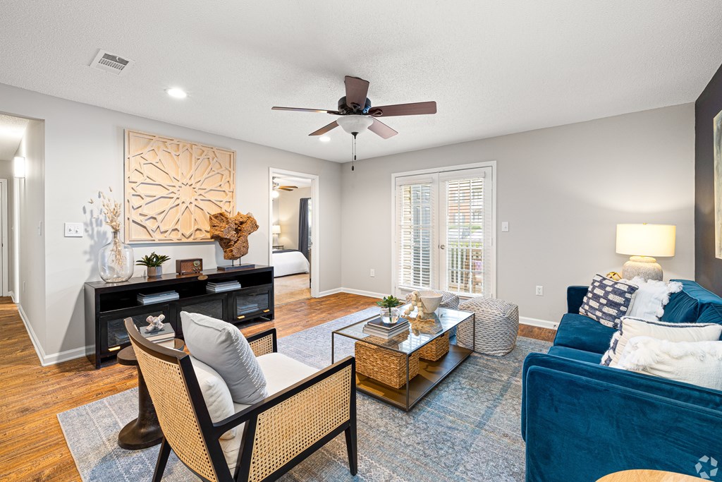A living room with a ceiling fan and a blue couch. at Reserve at Park Place Apartment Homes, Hattiesburg, MS, 39402