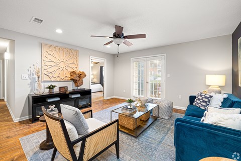 A living room with a ceiling fan and a blue couch. at Reserve at Park Place Apartment Homes, Hattiesburg, MS, 39402