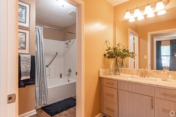 A bathroom with a sink, mirror, and shower at Reserve at Park Place Apartment Homes in Bossier City, LA