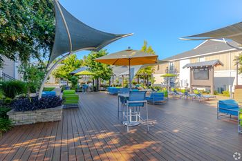 A wooden deck with blue chairs and a yellow umbrella at Reserve at Park Place Apartment Homes in Bossier City, LA