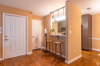 A kitchen area with a bar stool and a counter with hardwood floors at Reserve at Park Place Apartment Homes in Bossier City, LA