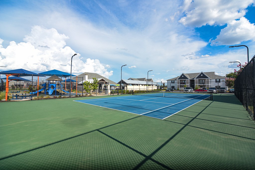 two tennis courts with houses and a playground in the background at Reserve of Bossier City Apartment Homes in Bossier City, Louisiana 71111