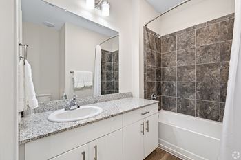 a bathroom with a sink and a shower and a mirror at The Met Apartment Homes, Hattiesburg, Mississippi
