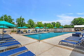 a pool with lounge chairs and umbrellas at the preserve at great pond apartments in winds