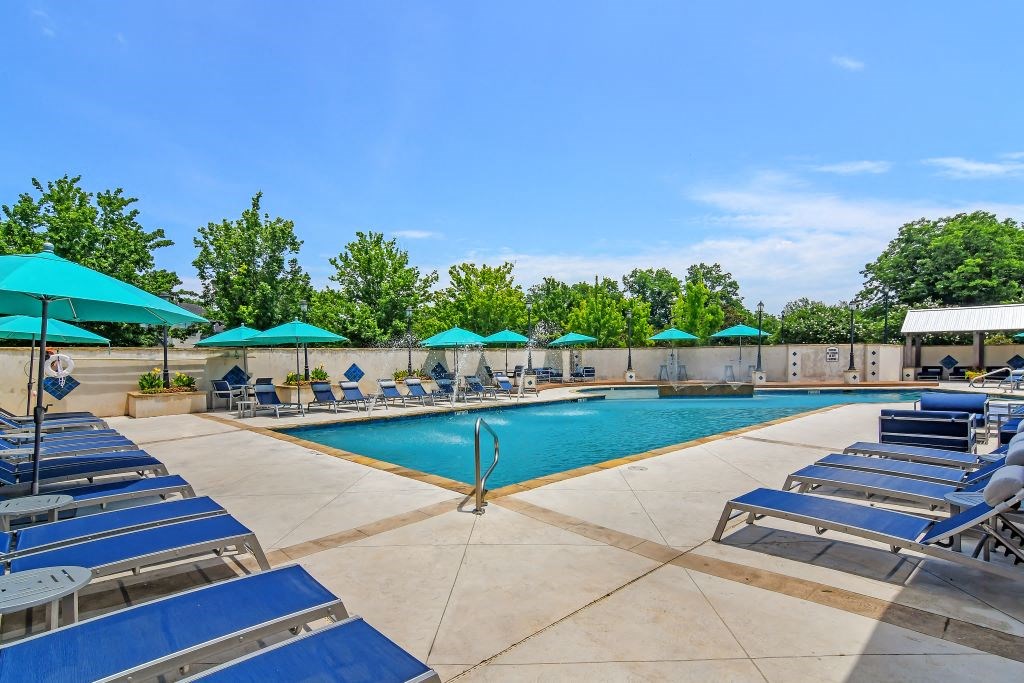 a pool with lounge chairs and umbrellas at the preserve at great pond apartments in winds  at Landing at Willow Bayou Apartment Homes, Louisiana
