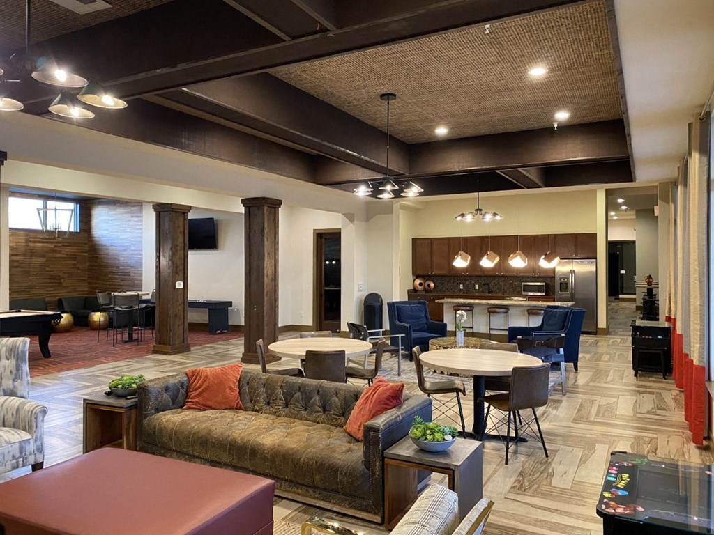a lobby with couches and tables and chairs and a kitchen at Retreat Apartments in Williston, ND 