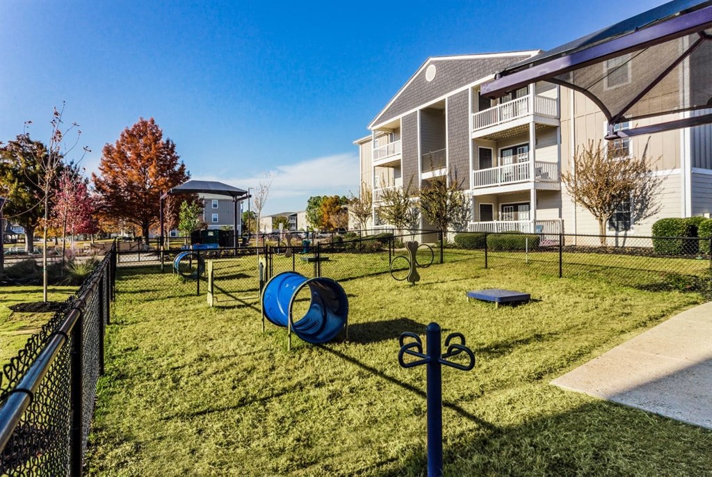A playground with a slide and a climbing frame is in front of a building  at Gulf Hills Apartment Homes in Ocean Springs, 39564