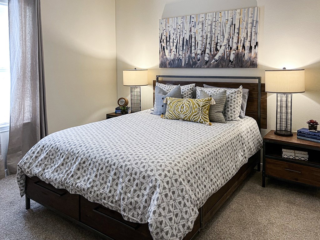 a bedroom with a bed and a painting on the wall at The Madison Apartment Homes in Tyler, TX 75703