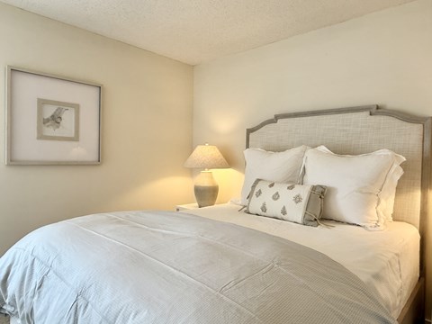 A bed with white pillows and a grey headboard is in the image at The Pointe Apartment Homes, Gautier, 39553