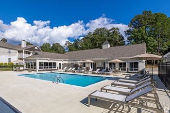 a swimming pool with lounge chairs in front of a building at Laurelwood Apartment Homes, Laurel, Mississippi, 39440