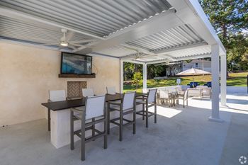 a patio with a bar and chairs and a tv on the wall  at Laurelwood Apartment Homes, Mississippi, 39440