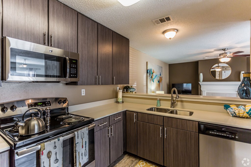 A kitchen with a stove, microwave, and sink. at Quail Ridge Apartment Homes, Bartlett