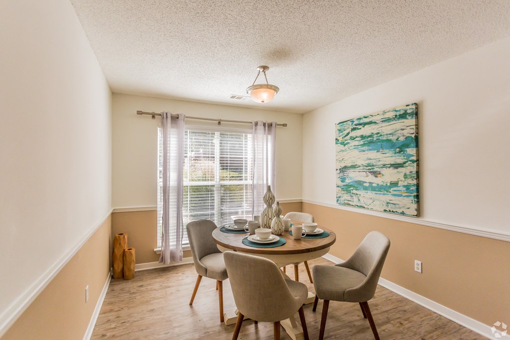 A dining room with a table set for two and a painting on the wall. at Quail Ridge Apartment Homes, Bartlett, 38135