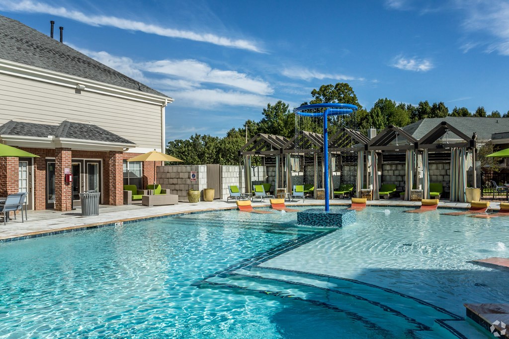 A large swimming pool with a blue umbrella and lounge chairs. at Quail Ridge Apartment Homes, Bartlett, 38135