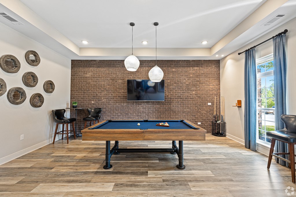 a living room with a pool table and a wall mounted tv at The Met Apartment Homes, Hattiesburg, 39402