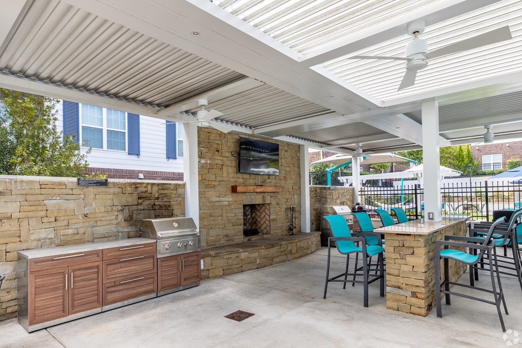 a covered patio with a grill and a table with chairs at The Met Apartment Homes, Mississippi