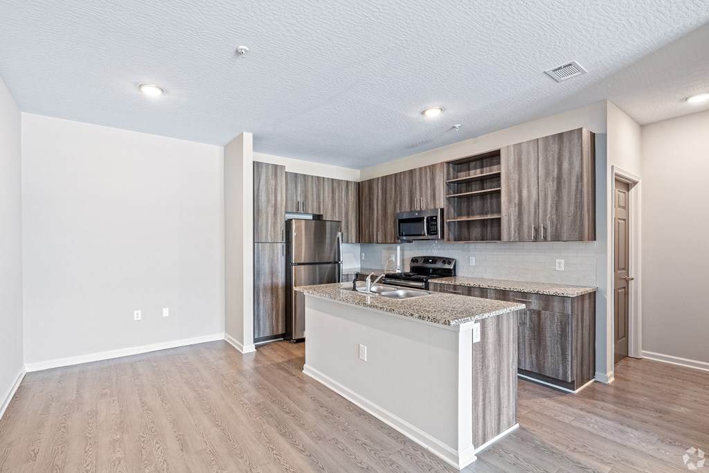 a kitchen with a island and a stainless steel refrigerator at The Met Apartment Homes, Hattiesburg, Mississippi
