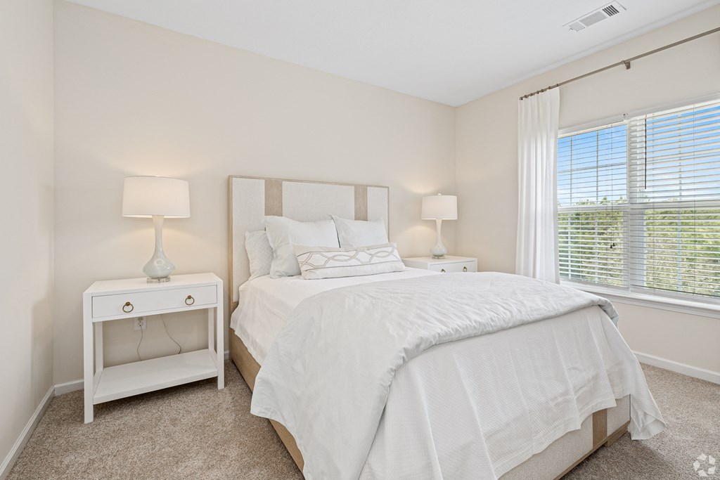 a bedroom with a large bed and a window at The Met Apartment Homes, Hattiesburg, MS, 39402