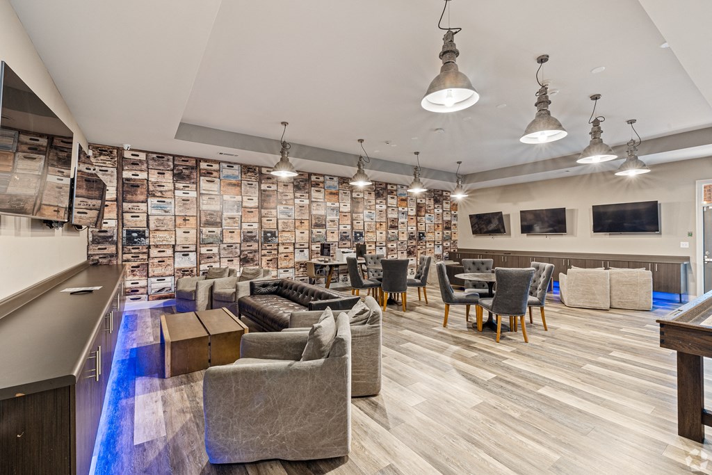 a lounge area with couches chairs and tables and a bar at The Met Apartment Homes, Hattiesburg