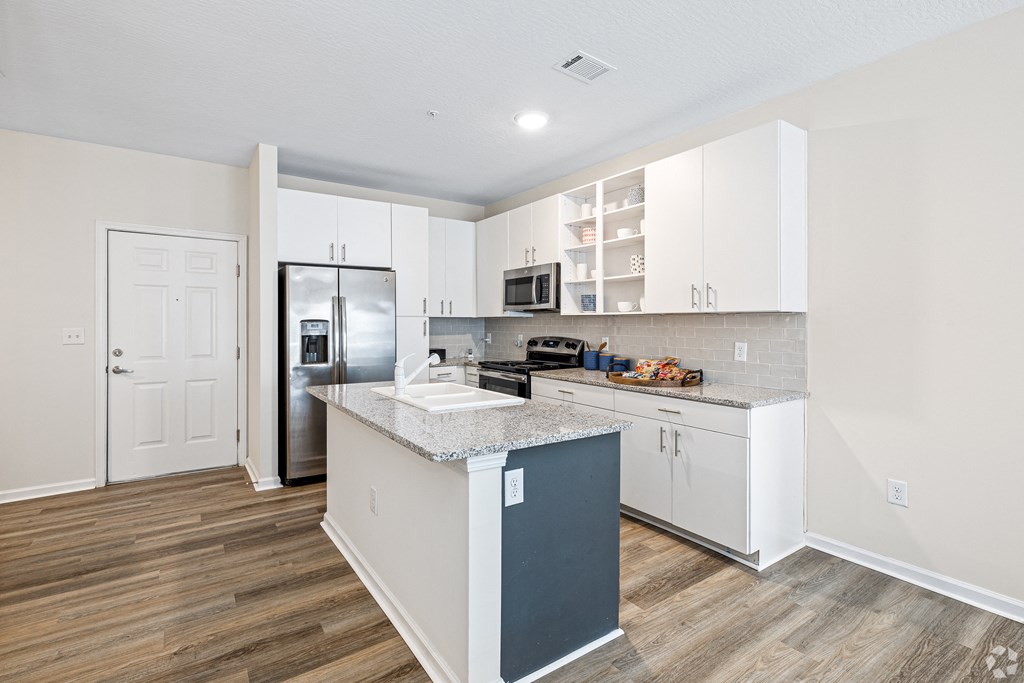 a kitchen with white cabinets and a stainless steel refrigerator at The Met Apartment Homes, Hattiesburg, Mississippi