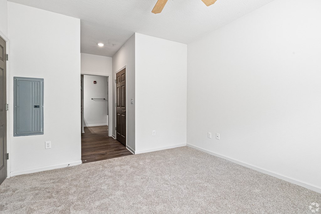 an empty living room with white walls and a door to a hallway at The Met Apartment Homes, Mississippi