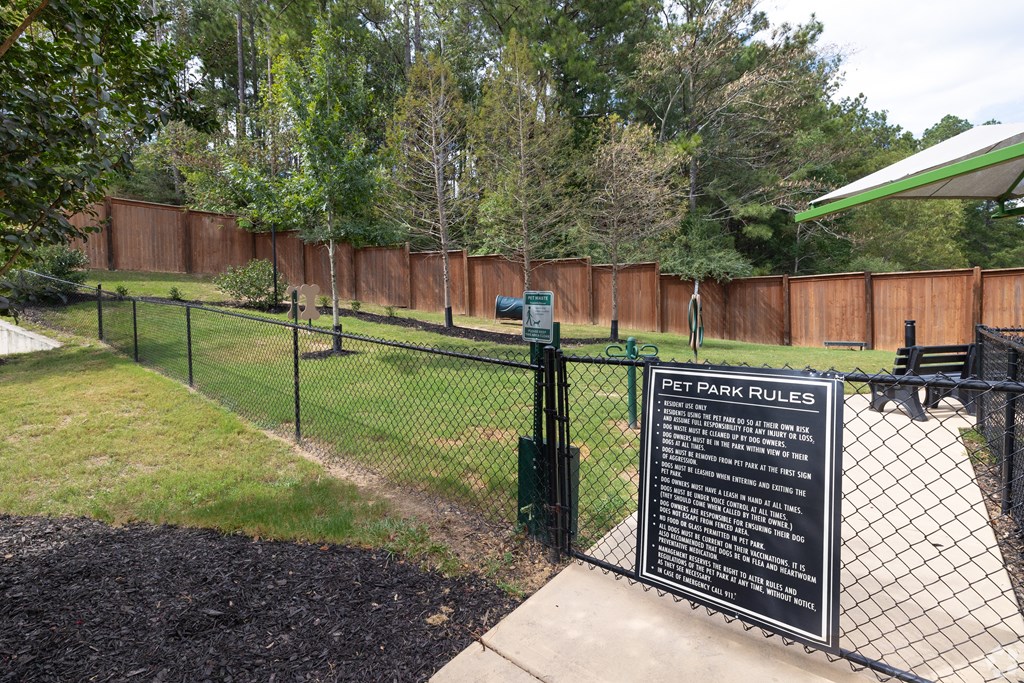 a dog park with a sign on a chain link fence at The Met Apartment Homes, Hattiesburg