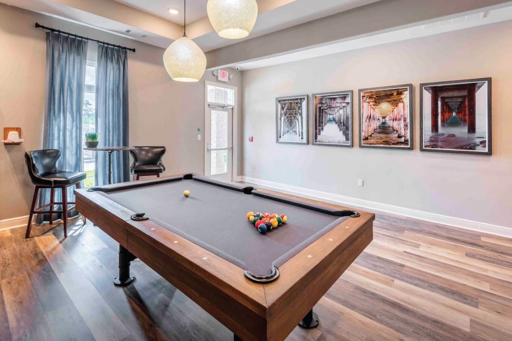 a pool table in a living room with pictures on the wall