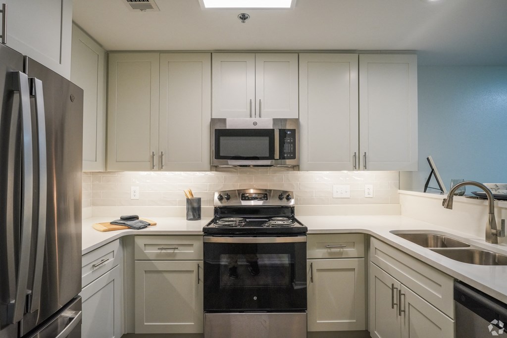 a kitchen with white cabinets and a stove and a microwave at The Vineyard at Castlewoods Apartment Homes in Brandon, Mississippi