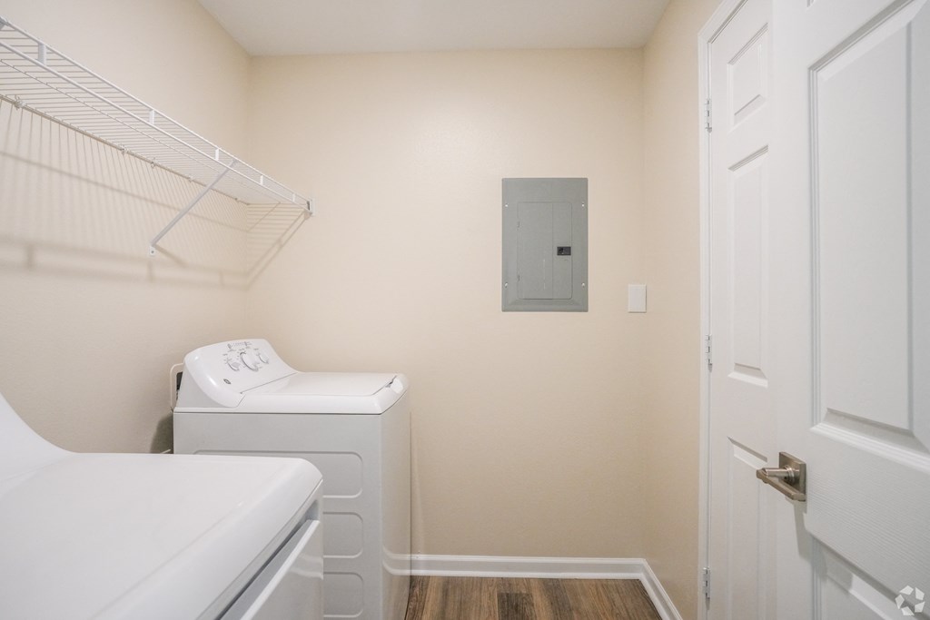 a laundry room with a washer and dryer and a door to a closet at The Vineyard at Castlewoods Apartment Homes in Mississippi 39047