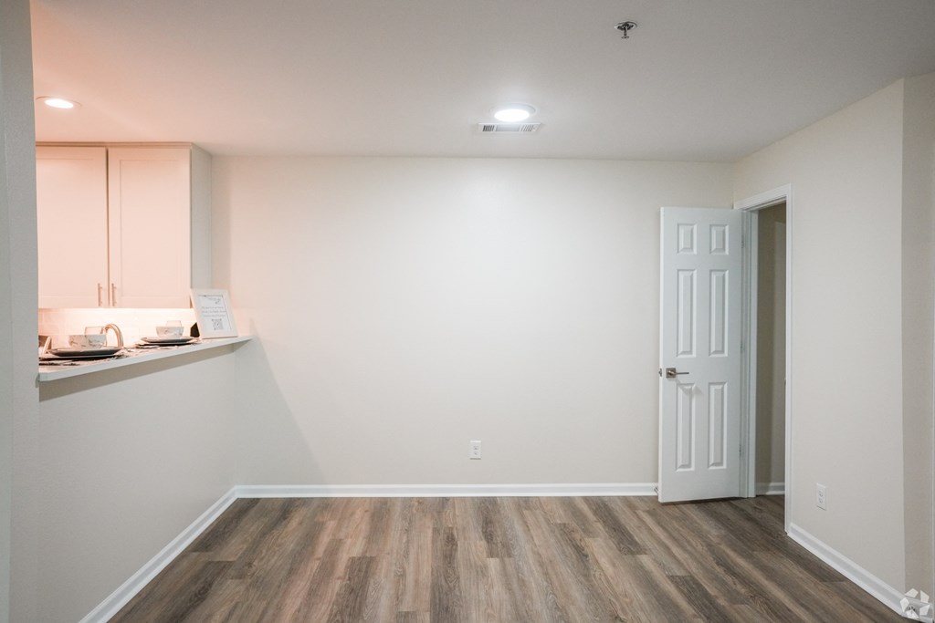 an empty room with a door and a kitchen at The Vineyard at Castlewoods Apartment Homes in Brandon, MS 39047