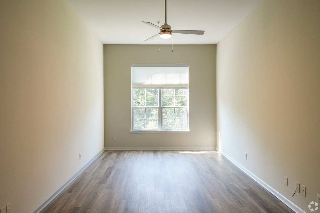 an empty room with a ceiling fan and a window at The Vineyard at Castlewoods Apartment Homes in Brandon, MS