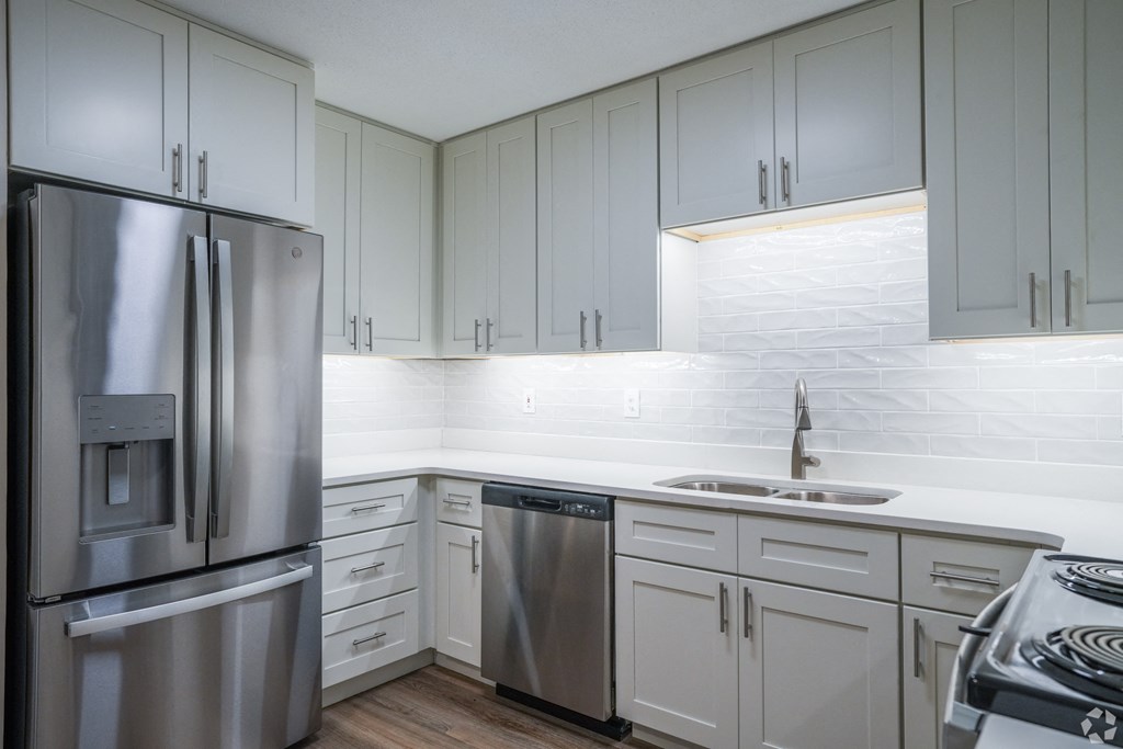 an all white kitchen with stainless steel appliances and white cabinets at The Vineyard at Castlewoods Apartment Homes in Mississippi 39047
