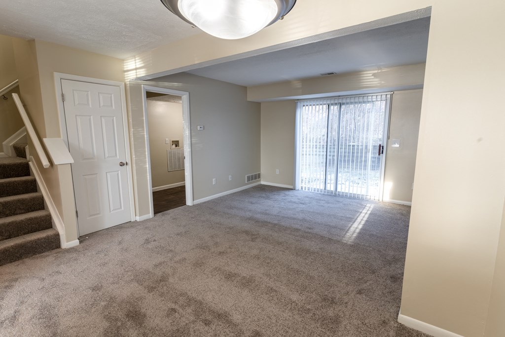 an empty living room with a staircase and a window