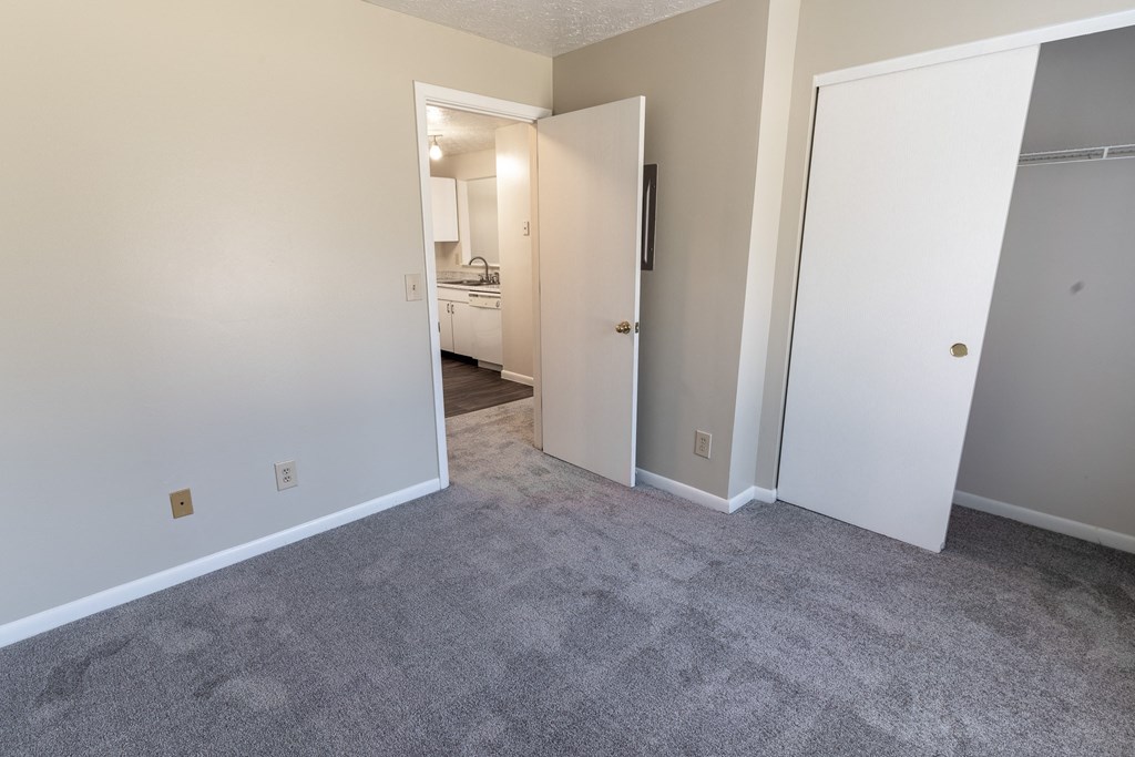a bedroom with a carpeted floor and a door to a closet