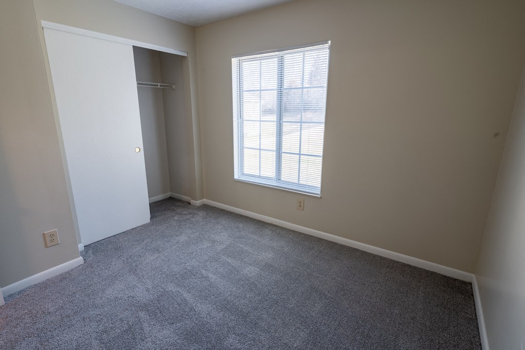 an empty room with a window and a closet