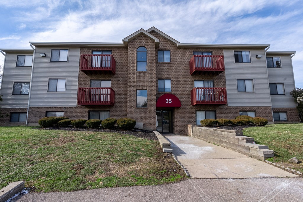 an apartment building with brick and white walls and red balconies