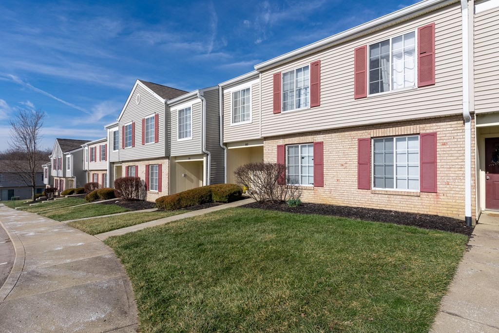 a row of houses with red shuttered windows on a sidewalk