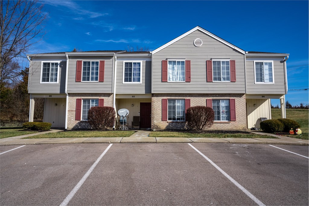 a large white house with red shutters and a parking lot