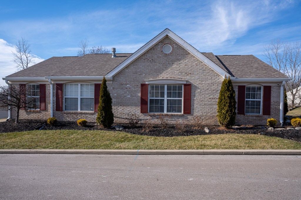 a brick house with red shutters and a lawn
