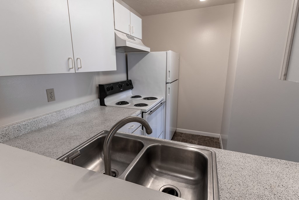 an empty kitchen with white appliances and white cabinets