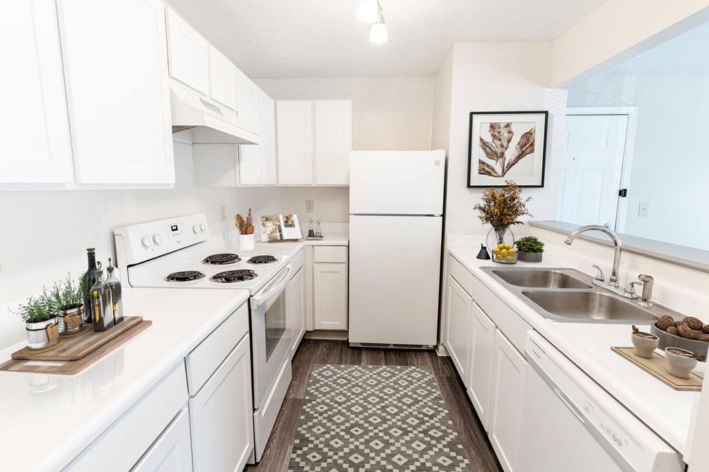 a white kitchen with a sink and a refrigerator