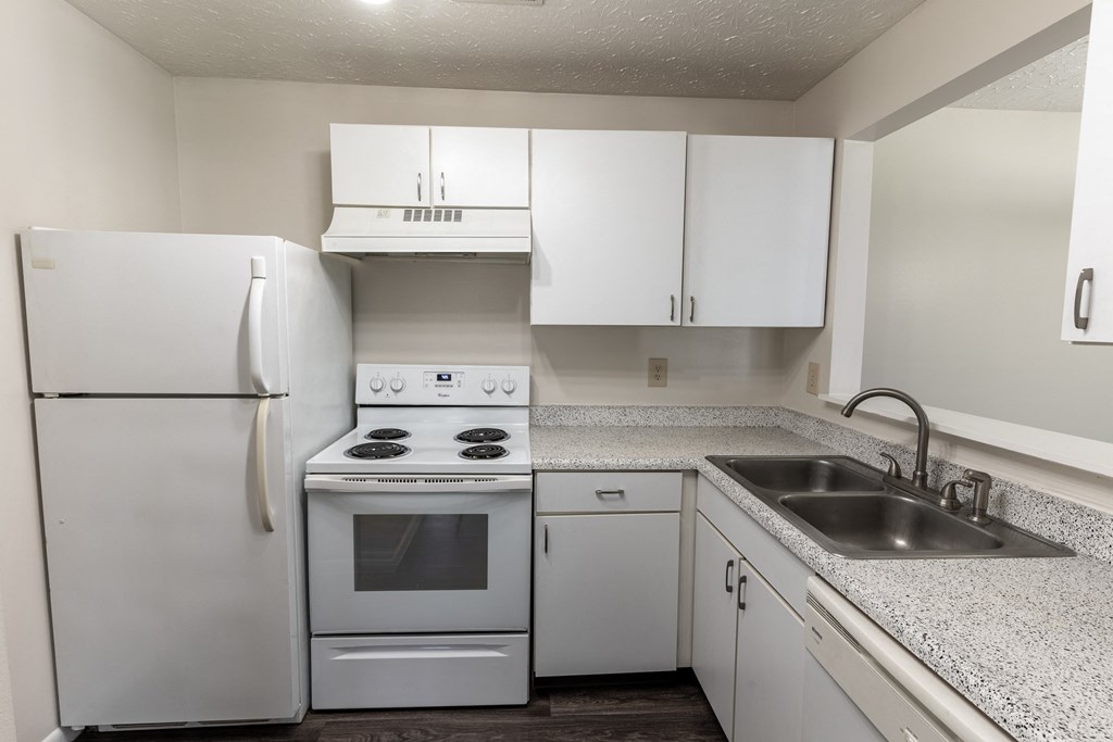 an empty kitchen with white cabinets and appliances and a sink