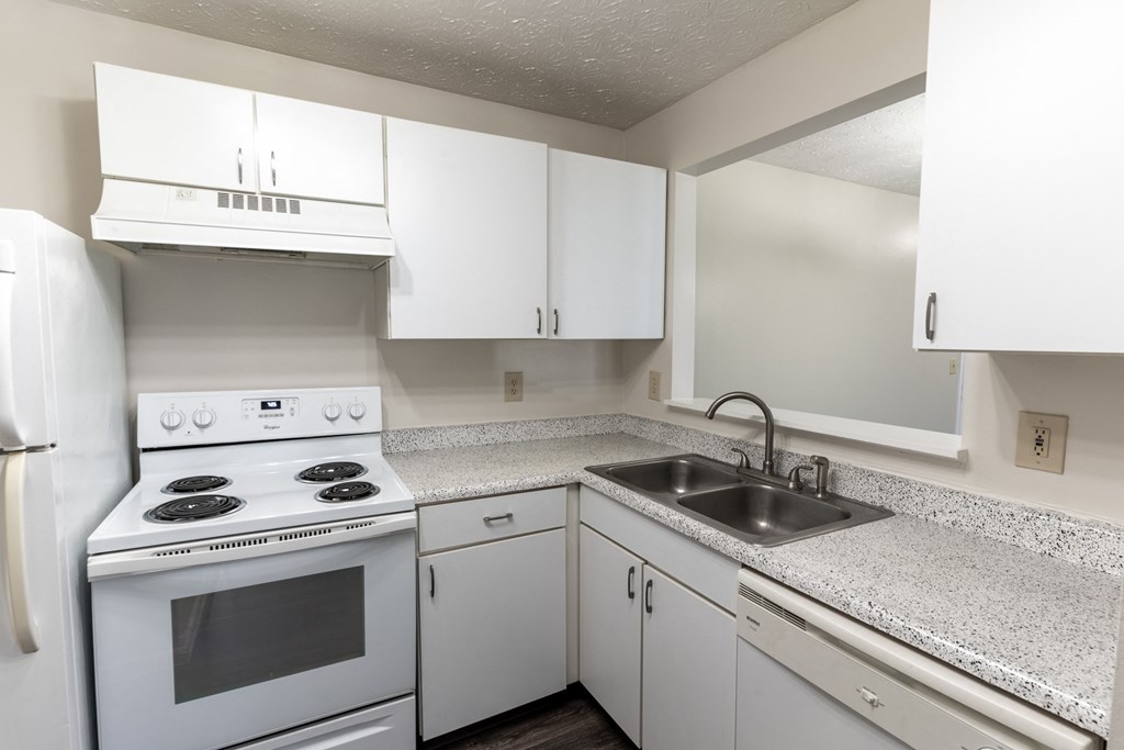 an empty kitchen with white appliances and white cabinets