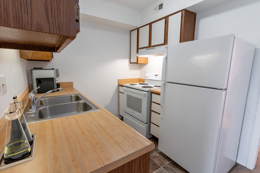 a kitchen with a white refrigerator freezer next to a stove top oven