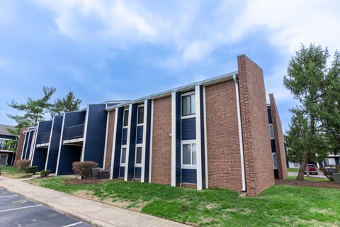 a brick building with blue siding and a grassy area in front of it