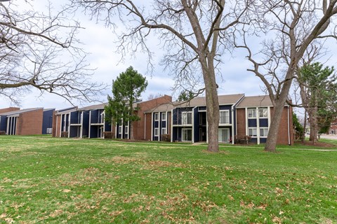 a grassy area with trees and buildings in the background