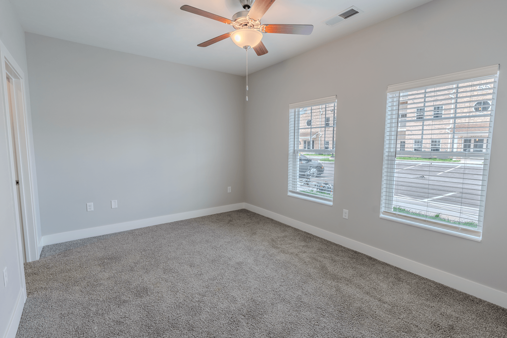 an empty living room with two windows and a ceiling fan at The Village at Sandstone Apartments, Greenwood, IN 46142
