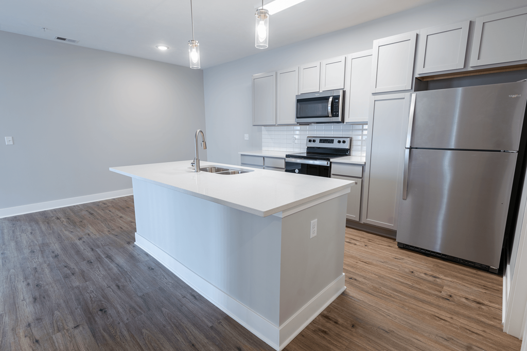 a kitchen with a large island and stainless steel appliances at The Village at Sandstone Apartments, Greenwood, IN