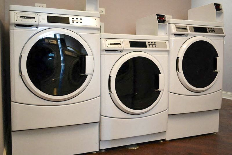 a row of white washing machines in a laundromat